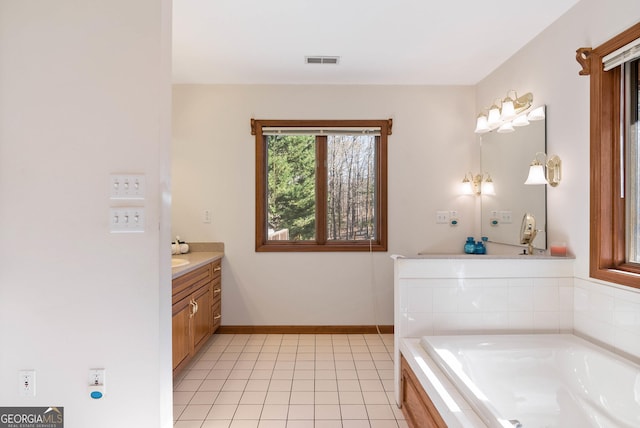 bathroom with tile patterned flooring, vanity, and a relaxing tiled tub