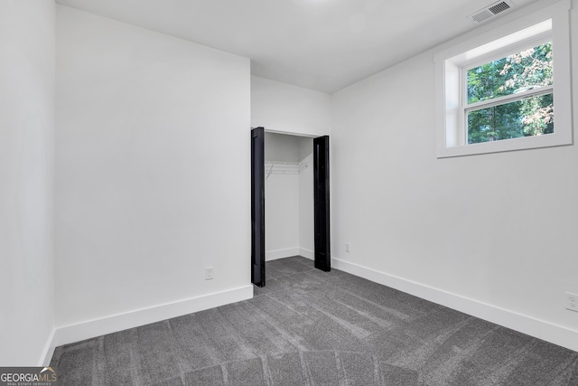 unfurnished bedroom featuring a closet and dark colored carpet