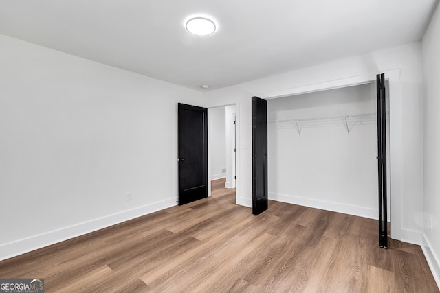 unfurnished bedroom featuring wood-type flooring and a closet