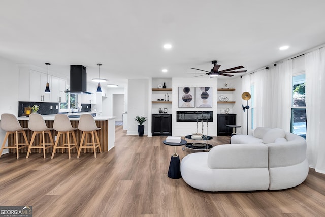 living room featuring ceiling fan, light hardwood / wood-style flooring, and a healthy amount of sunlight