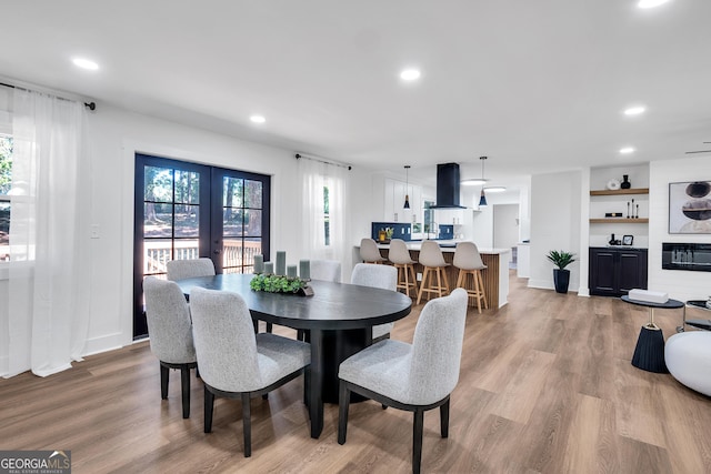 dining area featuring a large fireplace, light hardwood / wood-style floors, and french doors