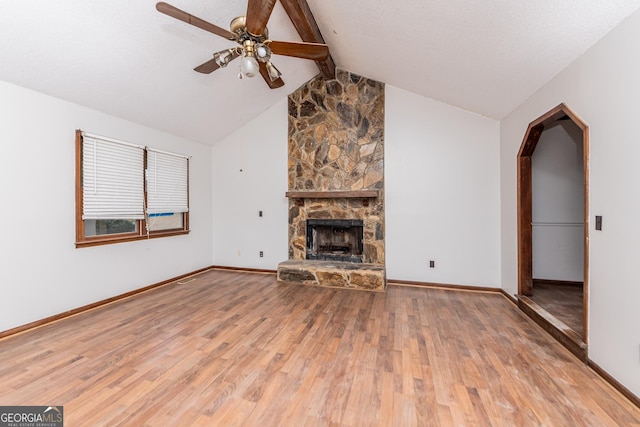 unfurnished living room featuring ceiling fan, a fireplace, lofted ceiling with beams, and wood-type flooring