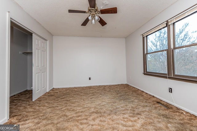 unfurnished bedroom featuring carpet flooring, a textured ceiling, a closet, and ceiling fan