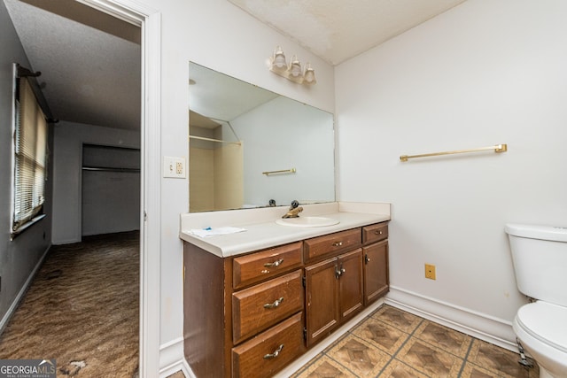 bathroom with a textured ceiling, vanity, and toilet