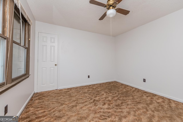 empty room with ceiling fan, carpet floors, and a textured ceiling