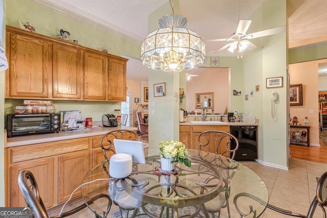 dining area with ceiling fan with notable chandelier, crown molding, light tile patterned floors, and sink