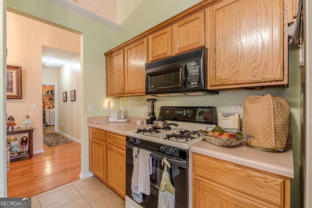 kitchen featuring white gas range oven, crown molding, and light tile patterned flooring