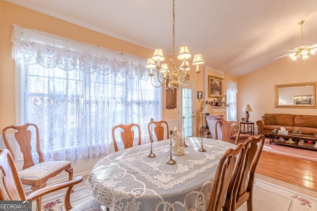 dining space featuring vaulted ceiling, light hardwood / wood-style flooring, and ceiling fan with notable chandelier