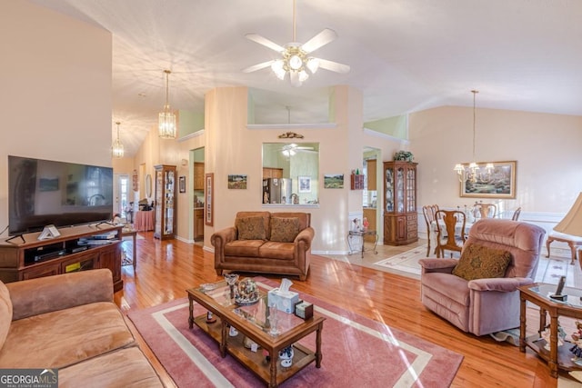 living room with ceiling fan with notable chandelier, high vaulted ceiling, and light hardwood / wood-style flooring