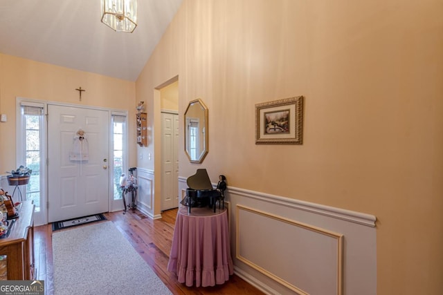 foyer featuring hardwood / wood-style flooring, vaulted ceiling, and an inviting chandelier