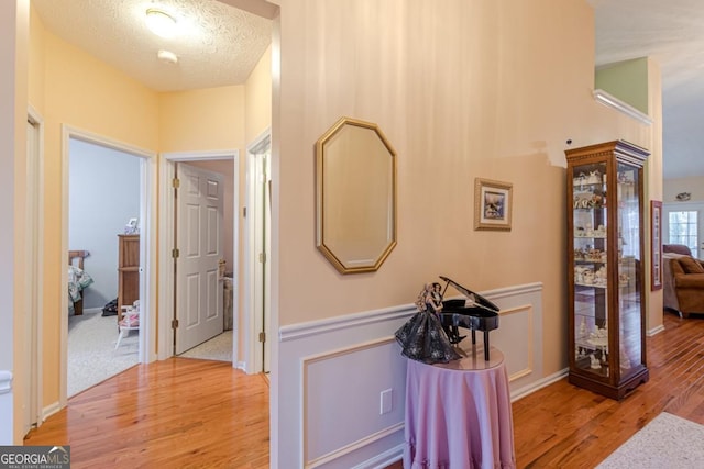 hallway with light hardwood / wood-style floors and a textured ceiling