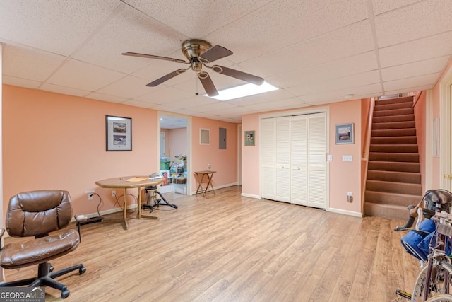 office with a paneled ceiling, ceiling fan, electric panel, and light hardwood / wood-style floors