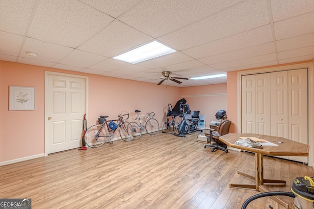 workout room featuring wood-type flooring, a drop ceiling, and ceiling fan