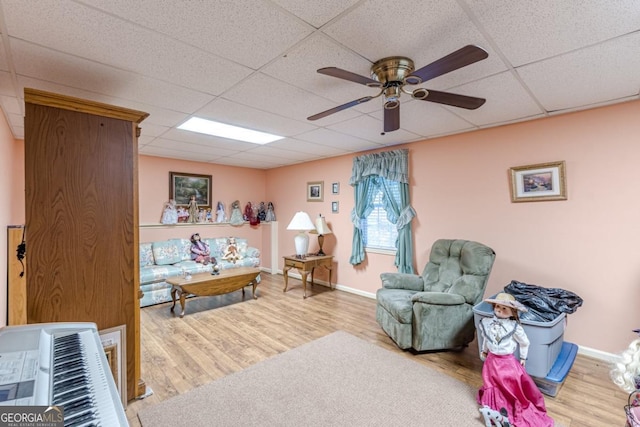 sitting room featuring hardwood / wood-style flooring, a drop ceiling, and ceiling fan