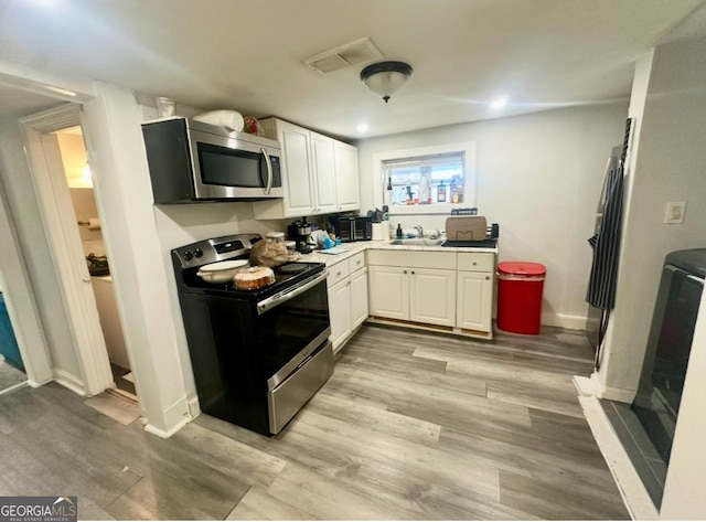 kitchen featuring light wood-type flooring, white cabinetry, and appliances with stainless steel finishes