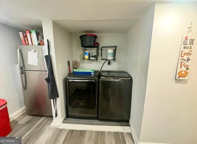 laundry room with washing machine and dryer and light hardwood / wood-style floors