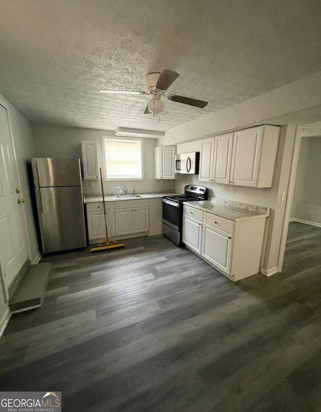 kitchen with a textured ceiling, stainless steel appliances, white cabinetry, and sink