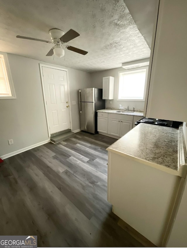 kitchen with dark wood-type flooring, sink, stainless steel fridge, a textured ceiling, and white cabinetry