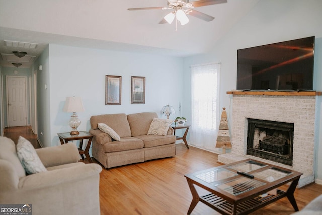 living room featuring a fireplace, wood-type flooring, vaulted ceiling, and ceiling fan