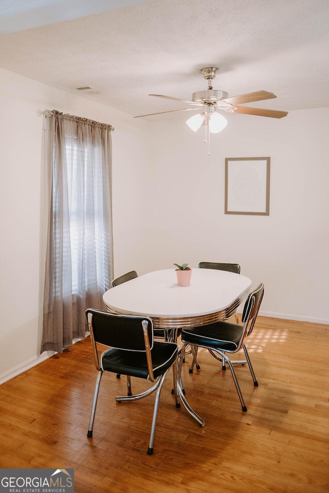 dining room featuring ceiling fan, wood-type flooring, and a textured ceiling