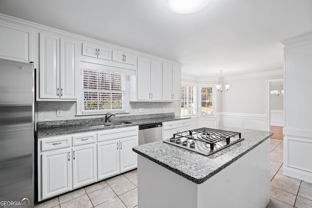 kitchen with a center island, white cabinets, sink, appliances with stainless steel finishes, and tasteful backsplash