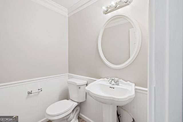 bathroom featuring toilet, ornamental molding, and sink