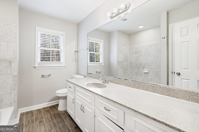 bathroom with hardwood / wood-style floors, vanity, toilet, and a shower