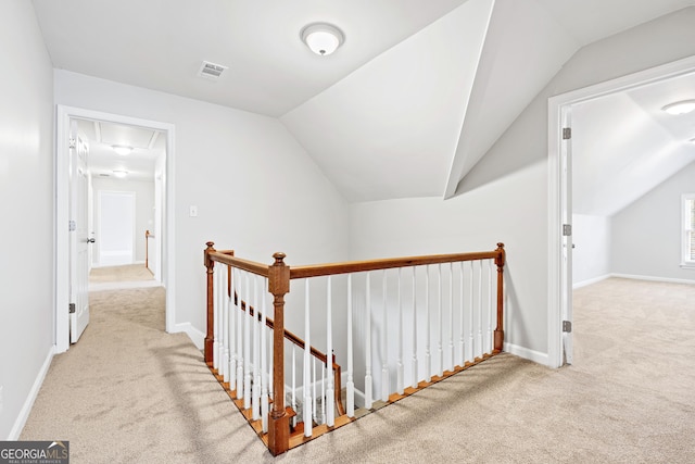 corridor with light colored carpet and vaulted ceiling