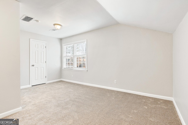 carpeted spare room with vaulted ceiling