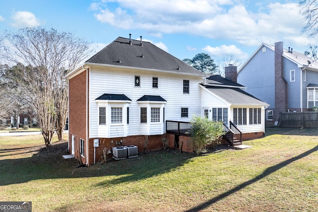 rear view of property with a lawn, a sunroom, central air condition unit, and a wooden deck