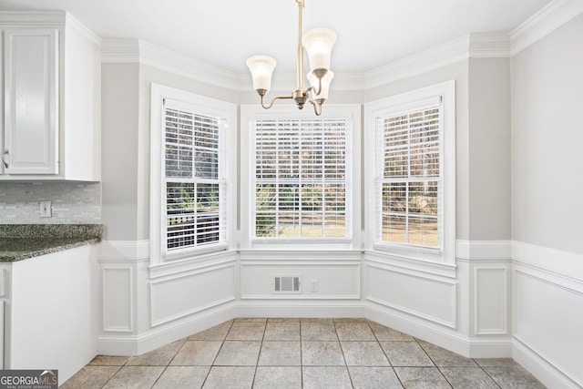 unfurnished dining area with plenty of natural light, light tile patterned flooring, ornamental molding, and a notable chandelier