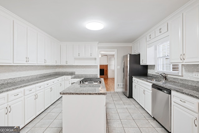 kitchen with white cabinetry, light stone countertops, a kitchen island, and appliances with stainless steel finishes