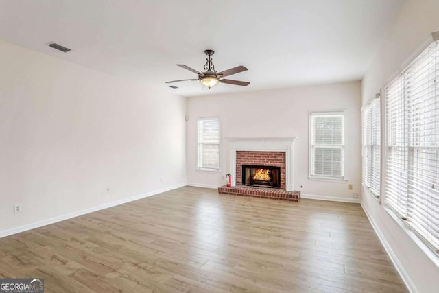 unfurnished living room featuring a fireplace, light hardwood / wood-style floors, and a wealth of natural light