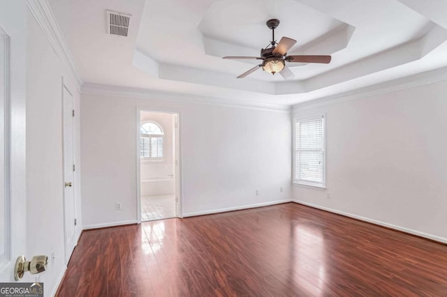 unfurnished room with dark wood-type flooring, a wealth of natural light, and a tray ceiling