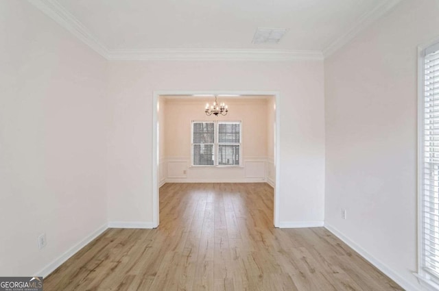 spare room with a chandelier, light wood-type flooring, and ornamental molding