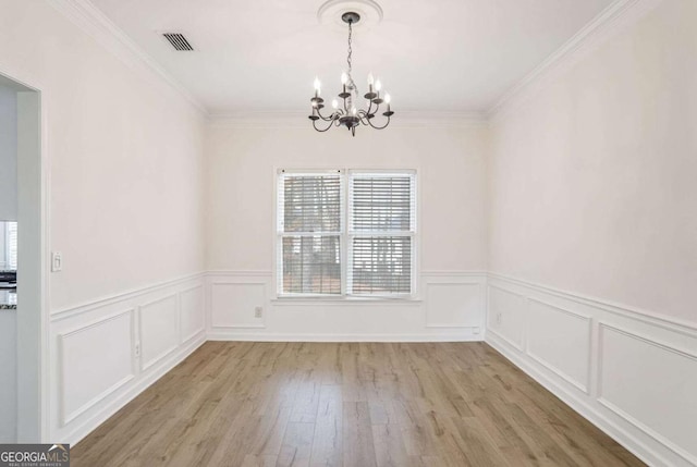 unfurnished dining area with a chandelier, light hardwood / wood-style floors, and crown molding