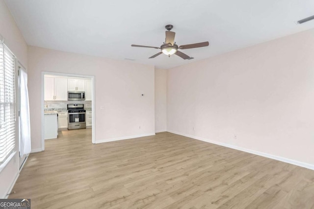 unfurnished living room featuring a wealth of natural light, ceiling fan, and light wood-type flooring