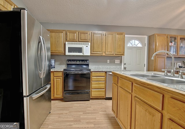 kitchen with a textured ceiling, light wood-type flooring, stainless steel appliances, and sink