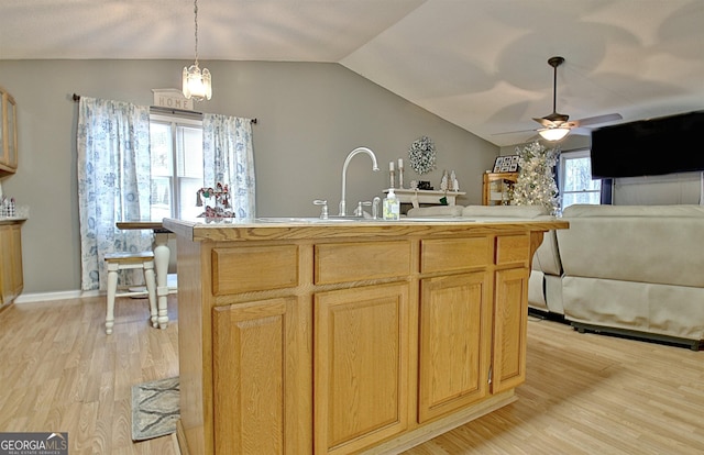 kitchen featuring vaulted ceiling, ceiling fan, light brown cabinets, light hardwood / wood-style flooring, and hanging light fixtures