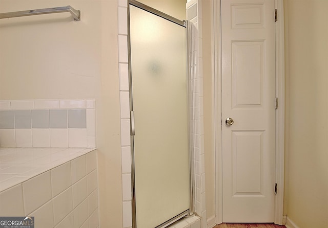 bathroom with a shower with shower door and hardwood / wood-style flooring