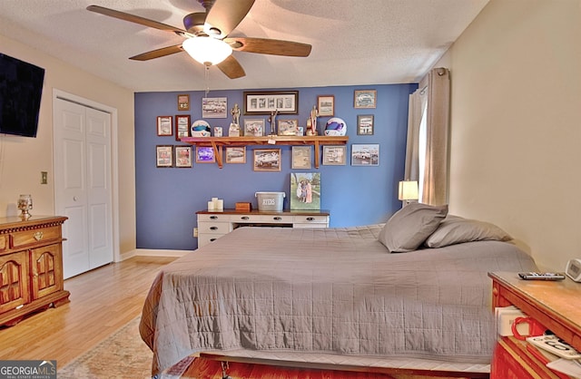 bedroom featuring ceiling fan, a closet, a textured ceiling, and light hardwood / wood-style flooring