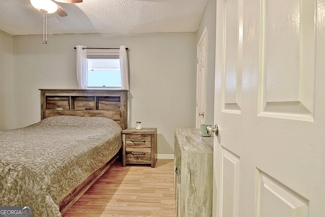 bedroom featuring ceiling fan, a textured ceiling, and light wood-type flooring