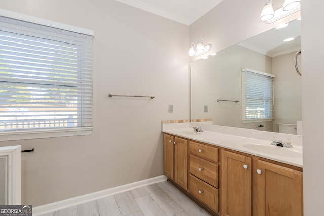 bathroom featuring crown molding, double vanity, toilet, a sink, and baseboards