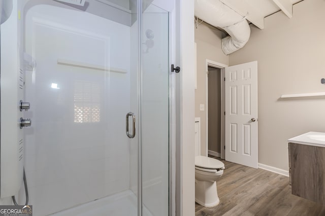 bathroom featuring toilet, wood finished floors, vanity, baseboards, and a shower stall