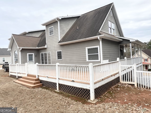 back of property with roof with shingles and a wooden deck