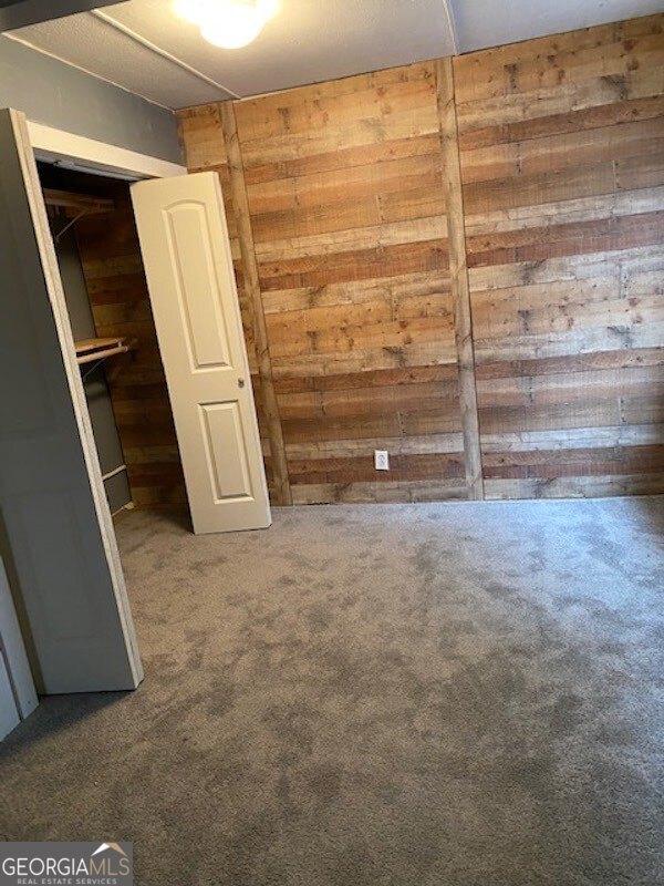 carpeted empty room with wood walls