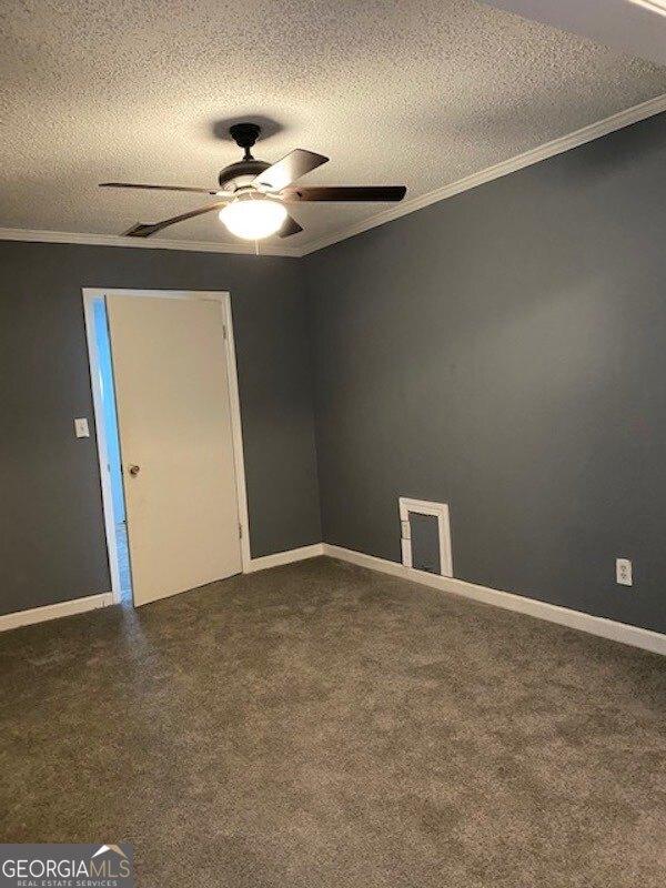 carpeted empty room featuring ceiling fan, a textured ceiling, and ornamental molding