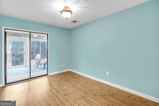 empty room with a textured ceiling and light hardwood / wood-style flooring