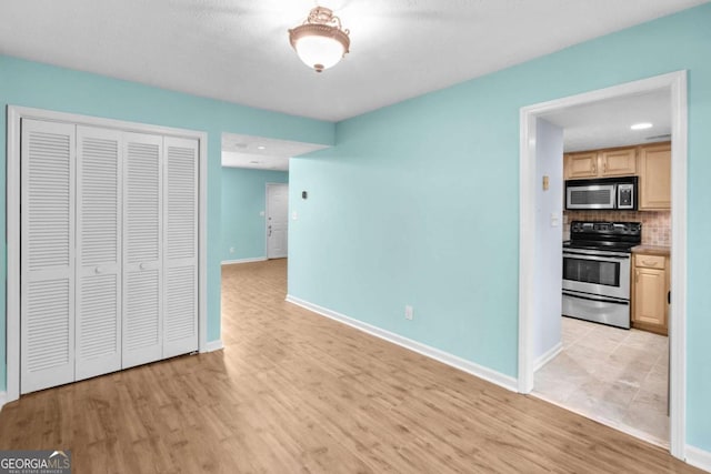 interior space featuring backsplash, light brown cabinets, stainless steel appliances, and light hardwood / wood-style flooring