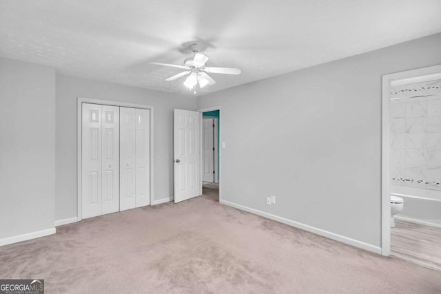 unfurnished bedroom with ensuite bath, ceiling fan, a textured ceiling, light colored carpet, and a closet